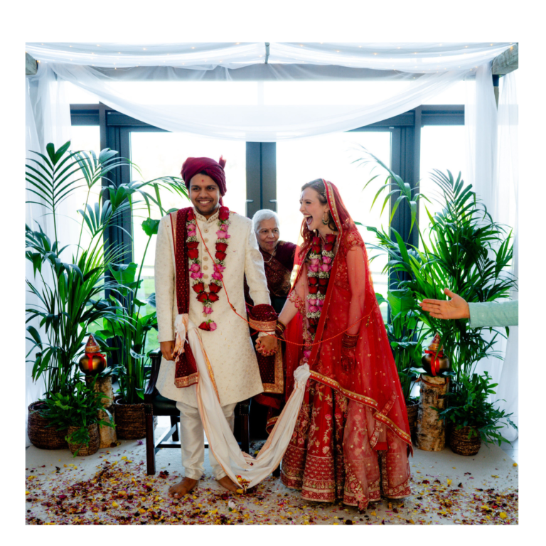 Mandap 12 Bride and groom laughing during a Hindu wedding ceremony beneath a botanical mandap with white draping and greenery