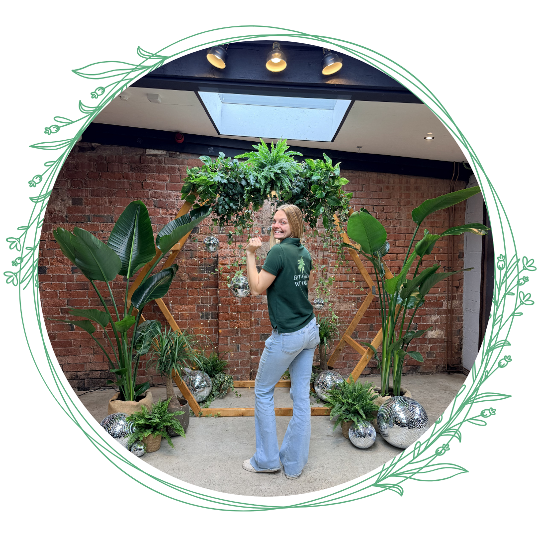 A Photo of Steph the owner of botanical weddings infront of a disco ball backdrop in a botanical weddings polo top