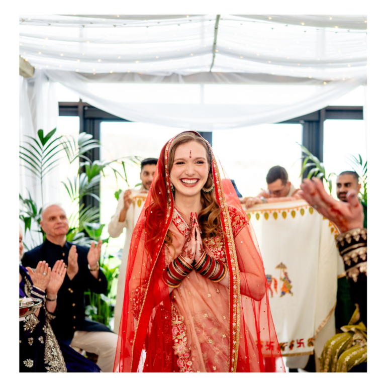 Mandap 13 Bride entering a Hindu wedding ceremony beneath a botanical mandap with white draping and greenery