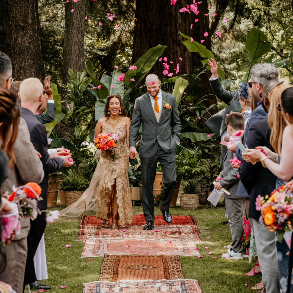 Bride and groom walking back down the aisle surrounded by living tropical plants for an outdoor botanical wedding ceremony.