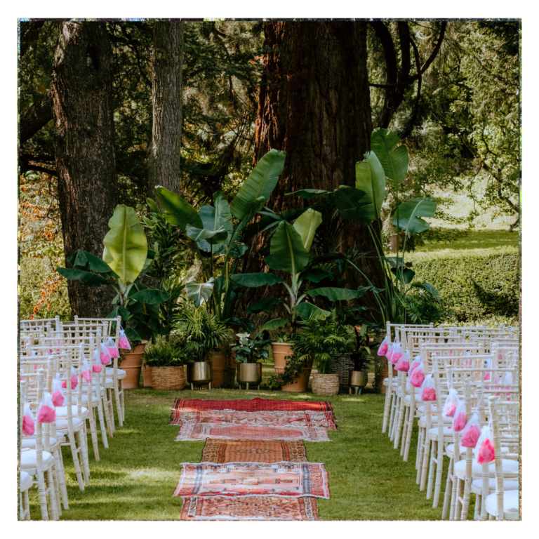 Outdoor wedding ceremony backdrop with banana plants, tropical greenery and botanical styling arranged beneath mature trees for a garden wedding ceremony.