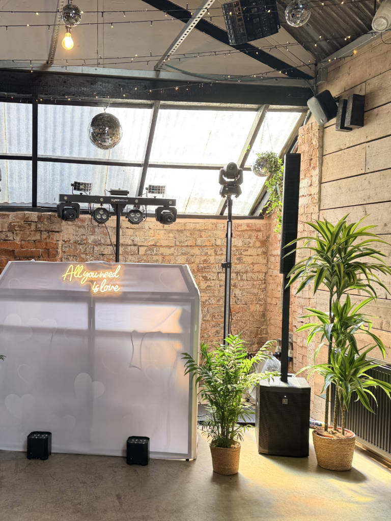 A Tropical style DJ Booth with dragon trees, palms and disco balls.