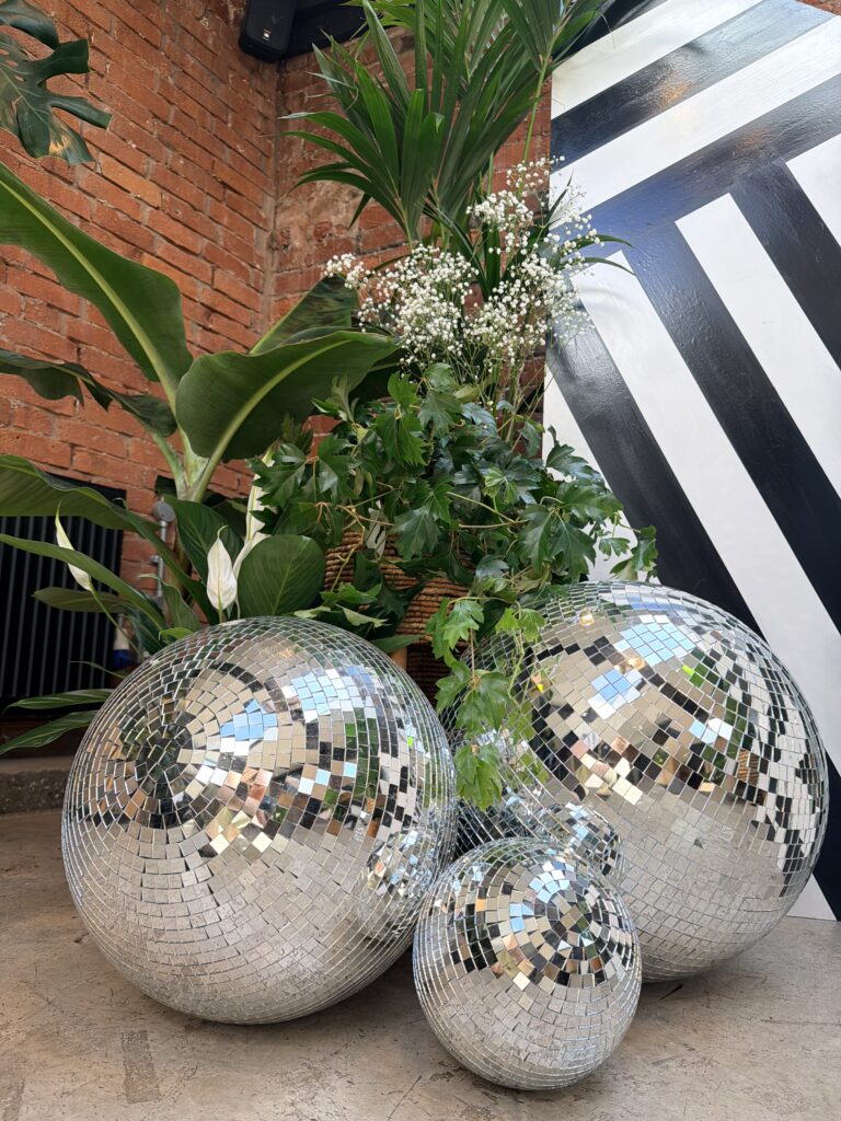 Disco balls on the floor of a ceremony backdrop in a industrial style venue