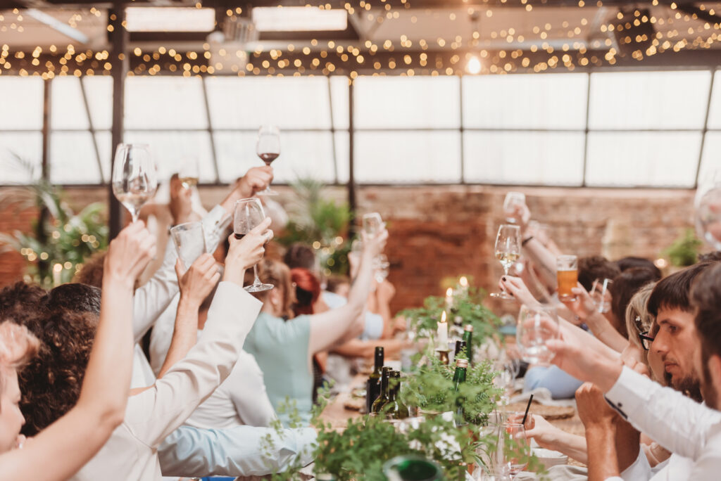 Guests celebrating around a long banquet table styled with living plants, tropical greenery and sustainable botanical wedding table décor.