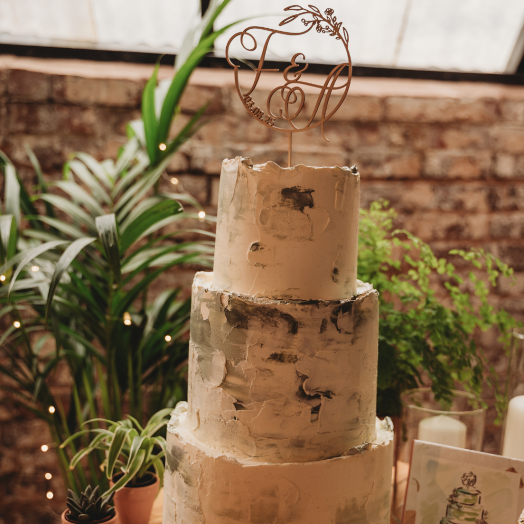 Rustic wedding cake surrounded by lush tropical plants creating a beautiful botanical wedding cake display.