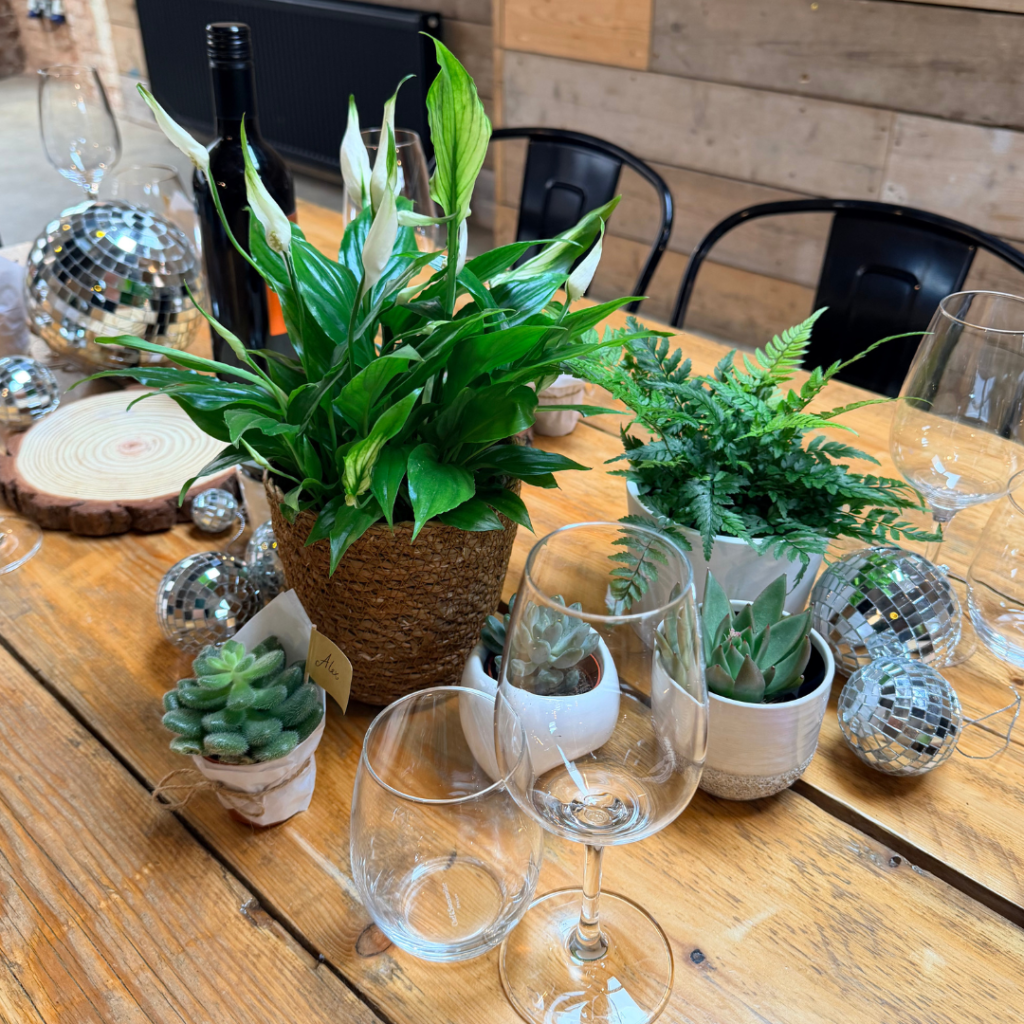 Wedding reception table featuring tropical plants, succulents and disco balls as unique botanical wedding centrepieces.