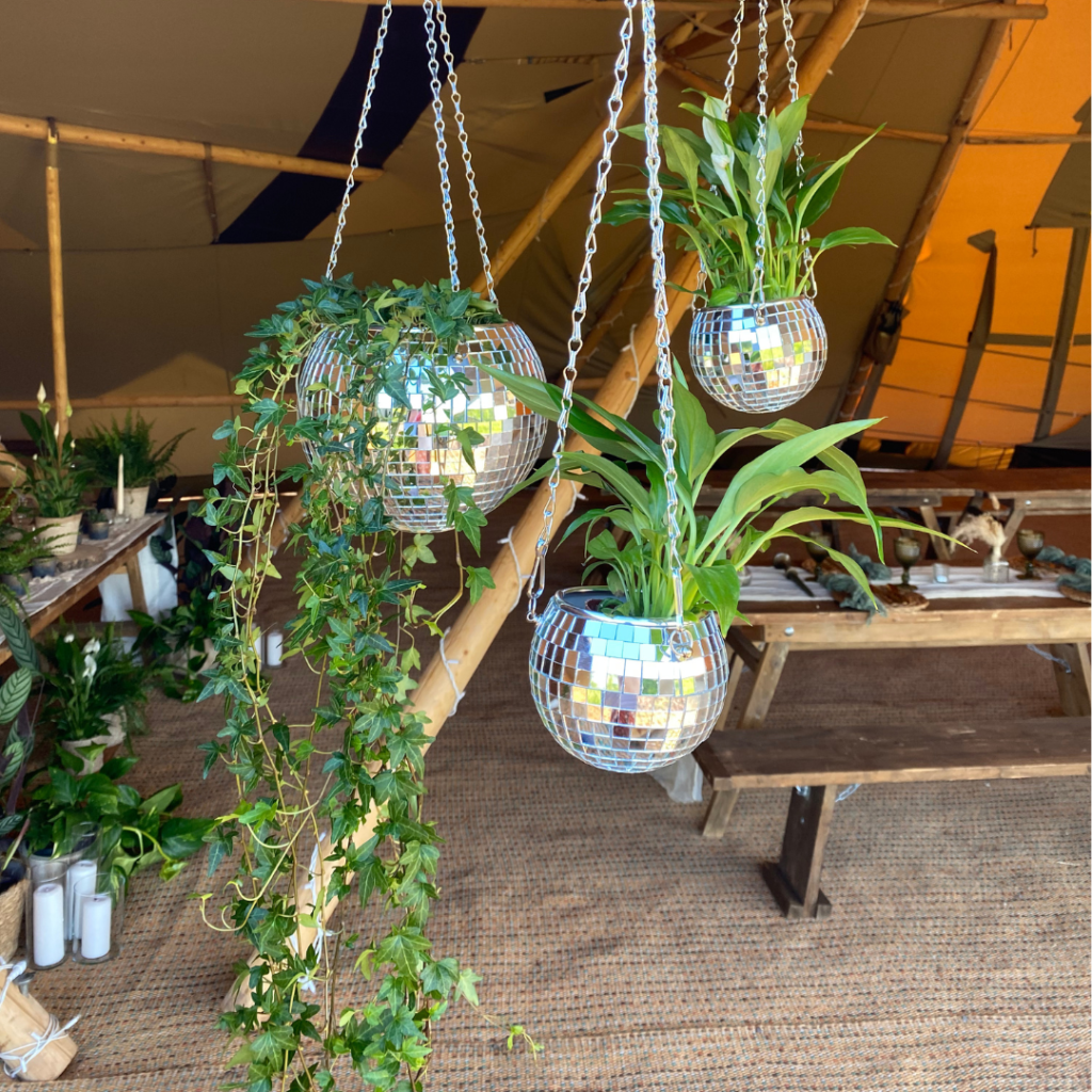 Wedding ceiling installation featuring hanging plants, disco balls and botanical décor creating an unforgettable reception space.