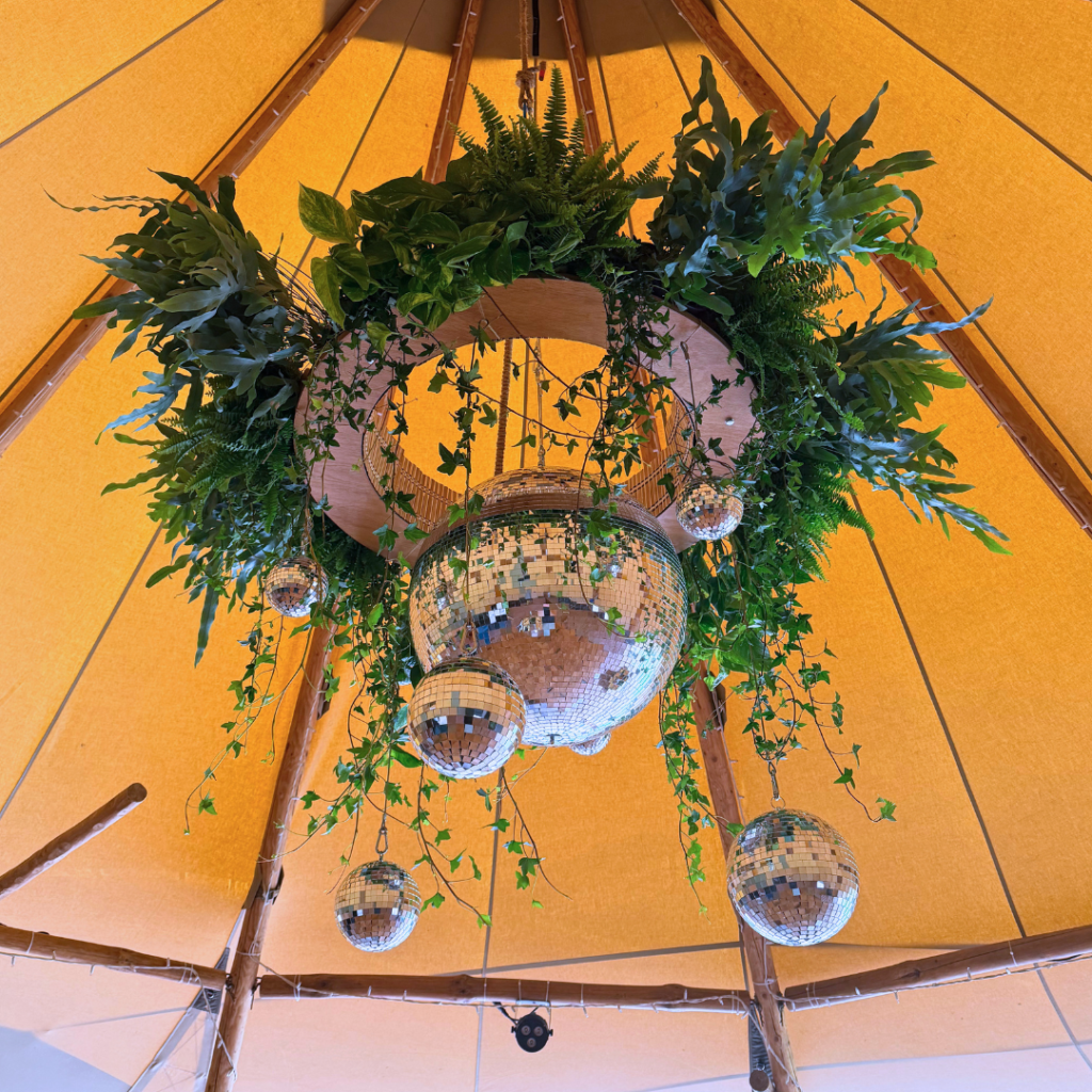 Living plant chandelier suspended above a wedding reception with disco balls creating dramatic botanical wedding styling.