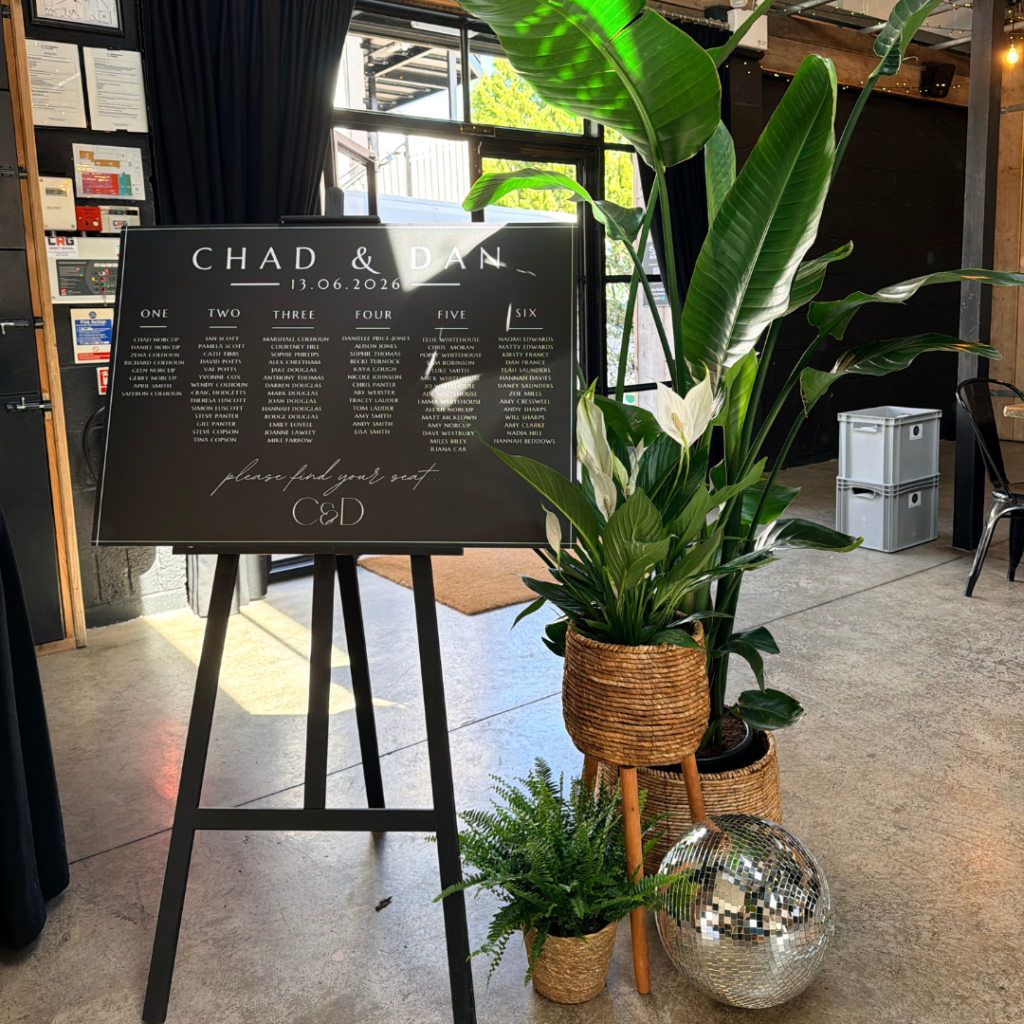 Wedding seating plan decorated with living plants, disco balls and tropical foliage creating a stunning botanical wedding display for guests to find their tables.