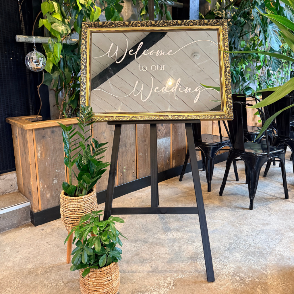 Botanical wedding welcome sign displayed with living plant décor