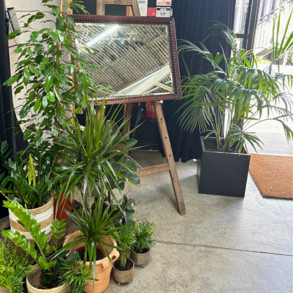 Standing plant arrangement adding greenery beside a wedding sign
