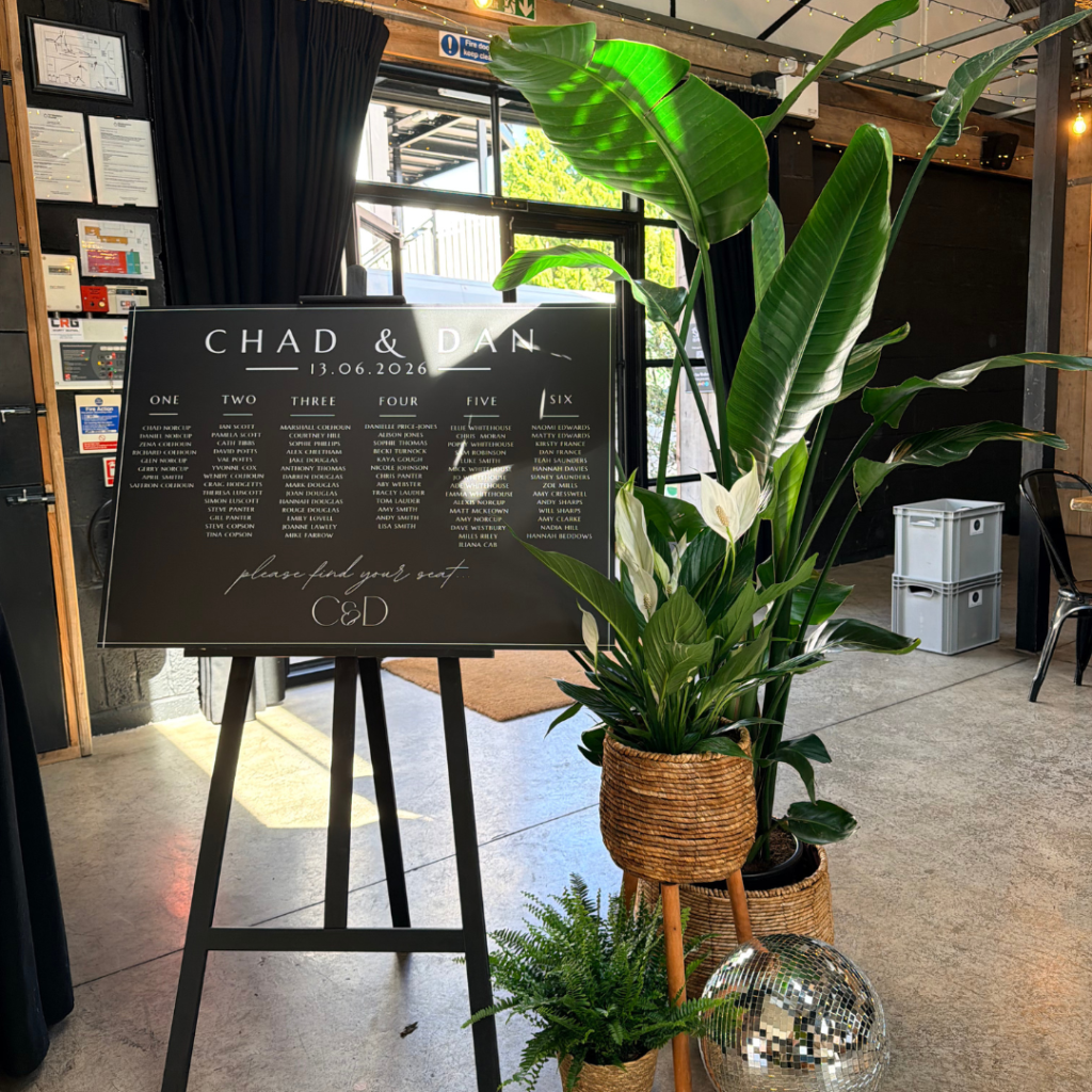 Black wedding seating plan framed with living potted plants